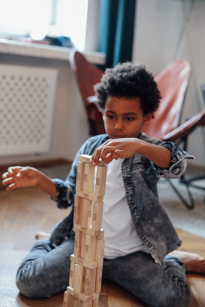 Young boy focused on stacking wooden blocks to build a tower indoors.